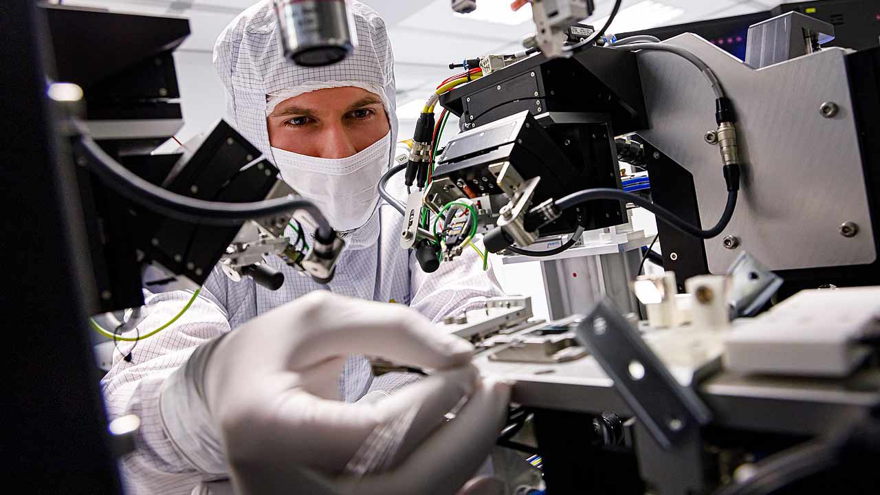 Ein Ingenieur an einem Mikroskop während er Halbleiterelektronik inspiziert